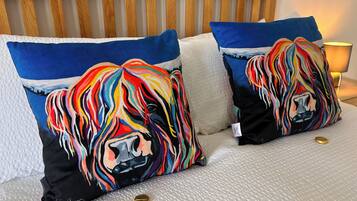 A bed with two colorful pillows, a wooden headboard, and a lamp.
