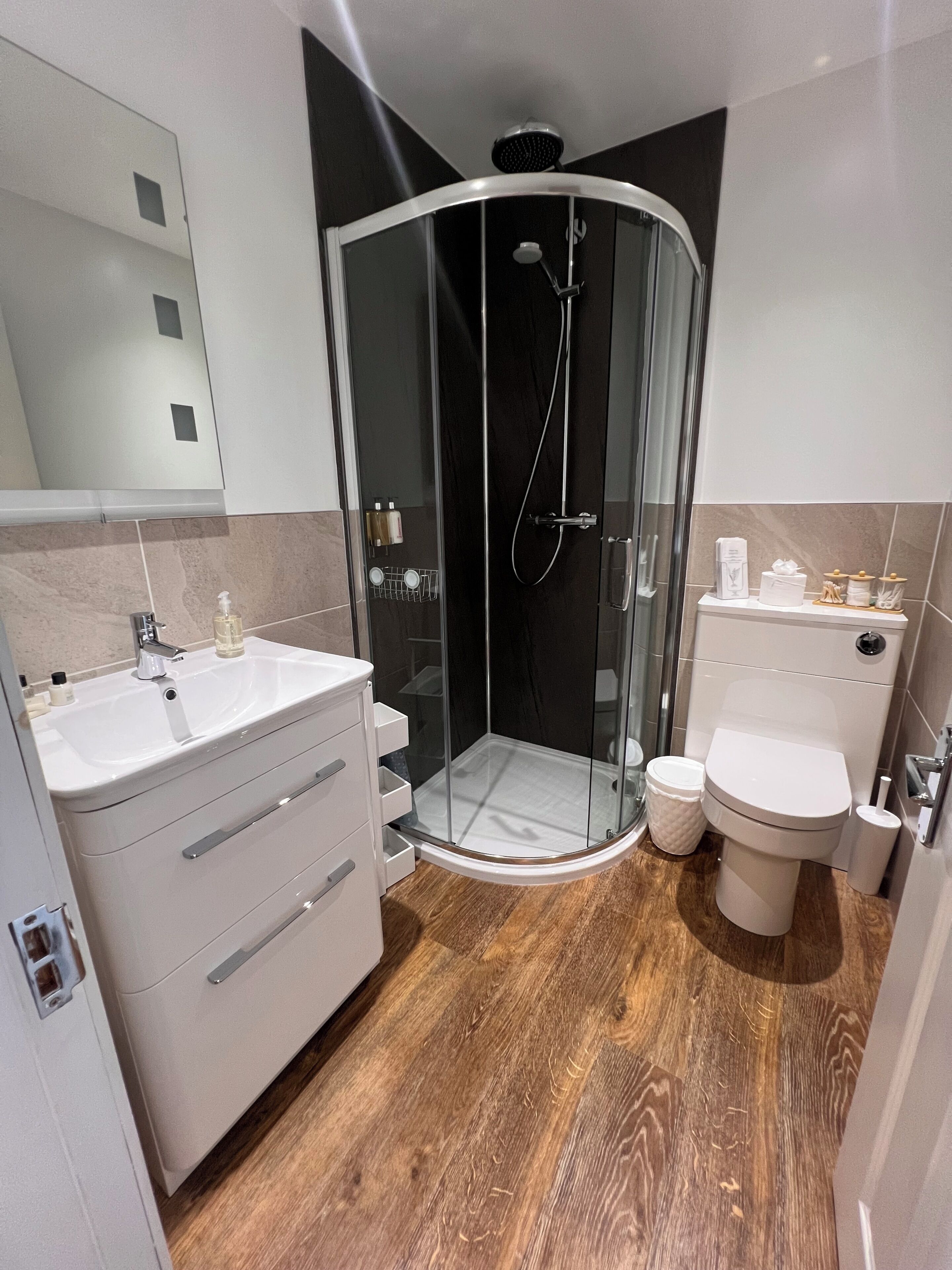 Une salle de bain moderne avec une douche à parois de verre, un lavabo blanc avec un miroir et des toilettes.