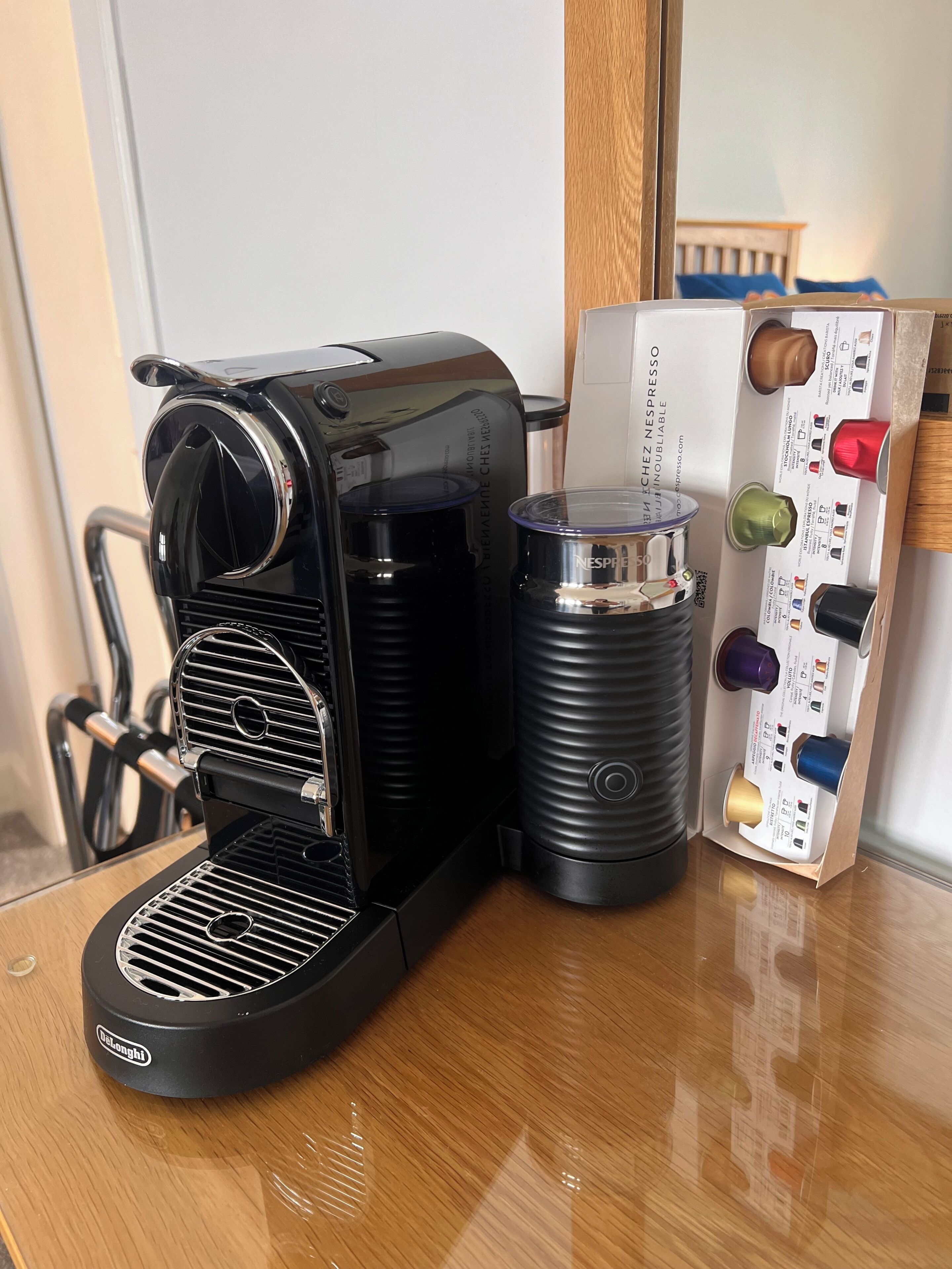 Een koffieapparaat met een lekbak, een houder voor koffiekapsules, en een handmatig koffiezetapparaat.