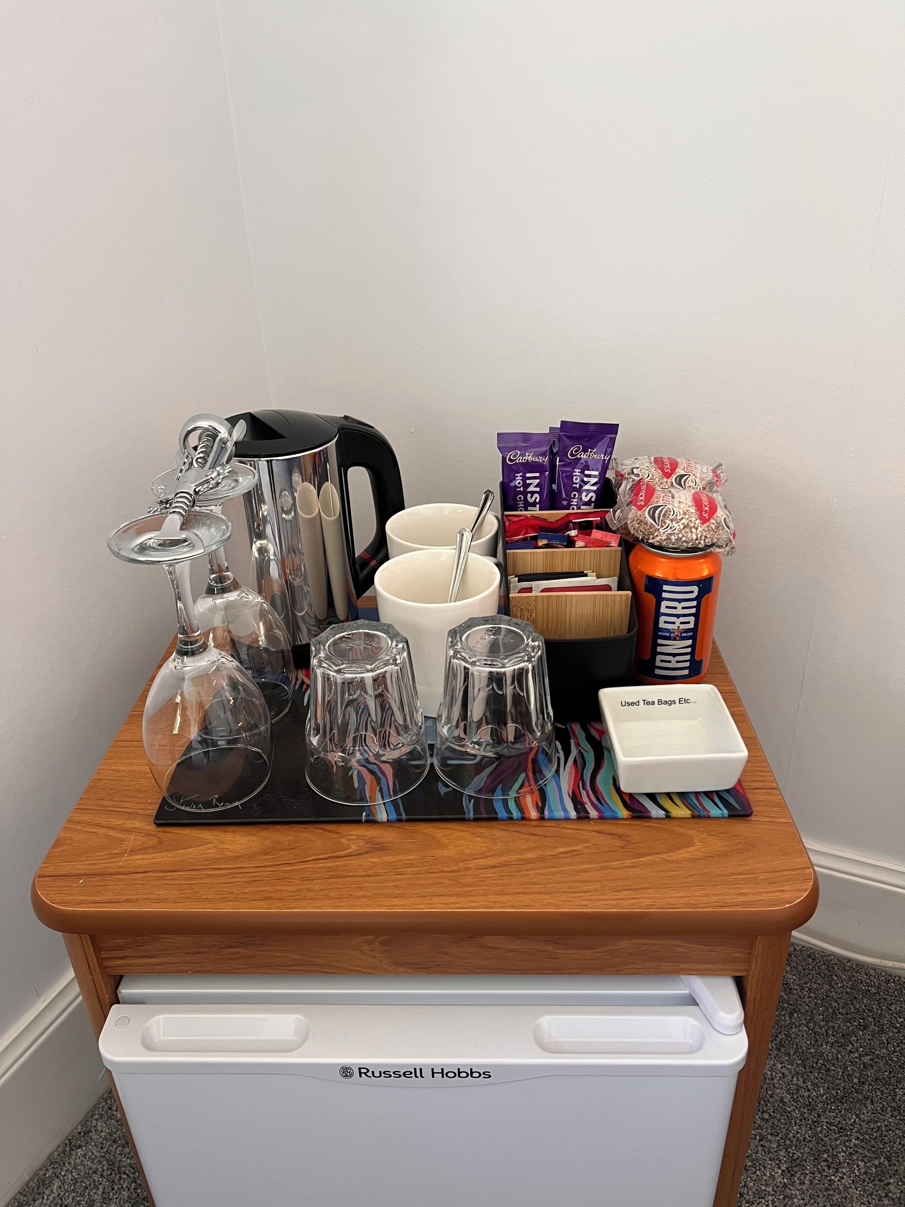 A tray with a teapot, cups, a box of tea bags, and a tin of popcorn.