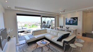 A modern living room with a large sectional sofa, a coffee table, and a dining area.