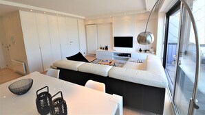 A modern living room with a sofa, a dining table, and a TV.