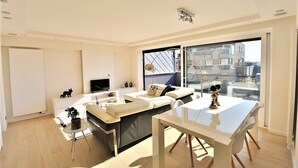 A modern living room with a sofa, TV, and dining table.