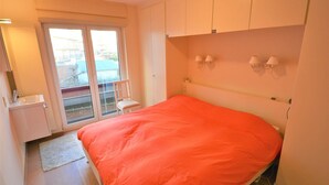 Une chambre à coucher comprenant un lit, une porte-fenêtre coulissante, une chaise et une petite table.