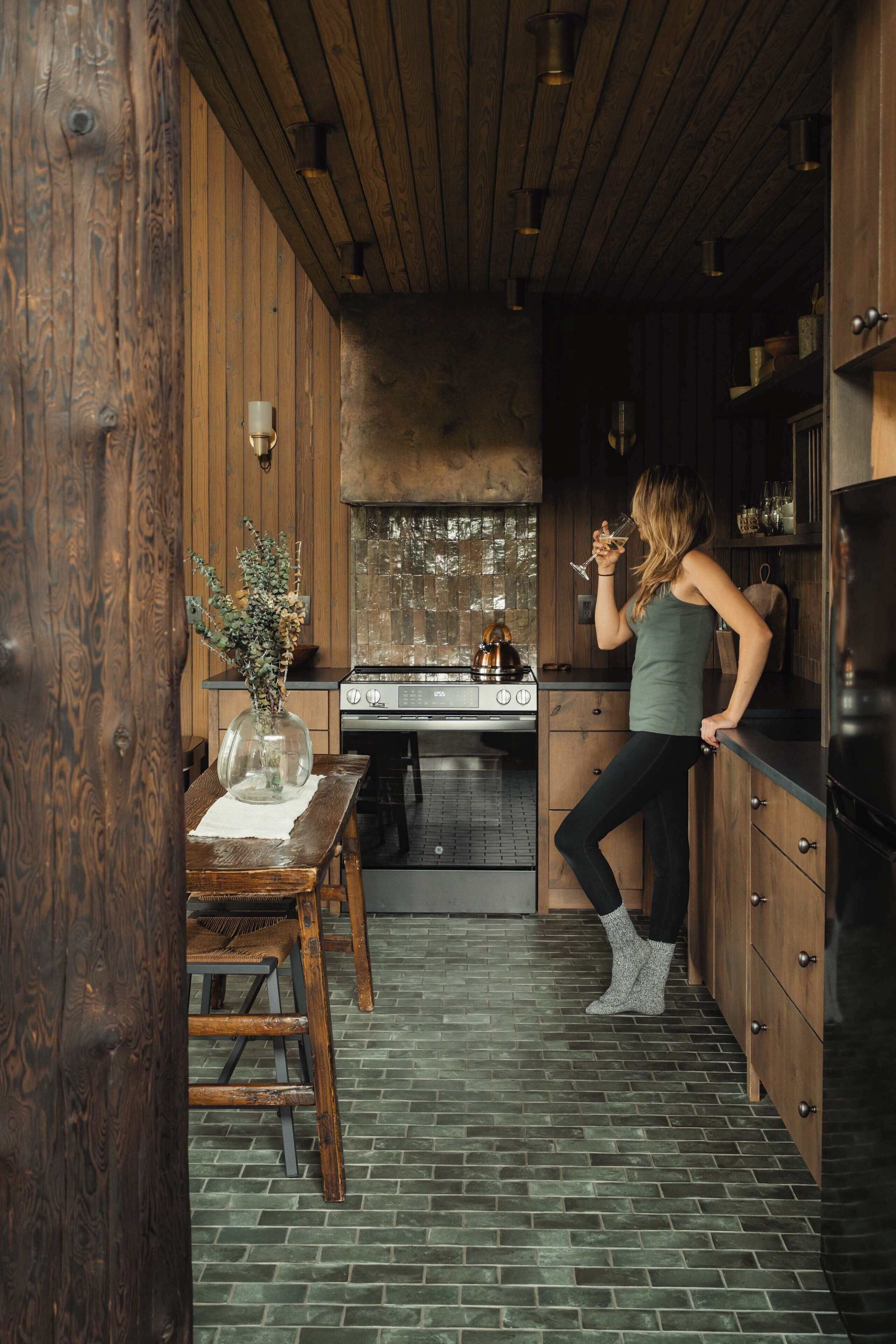 Een keuken met houten wanden, een fornuis en een persoon die een glas vasthoudt.