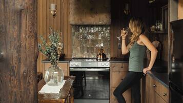 Een keuken met houten wanden, een fornuis en een persoon die een glas vasthoudt.