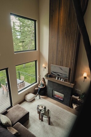 A spacious living room with a fireplace, large windows, and a cozy seating area.