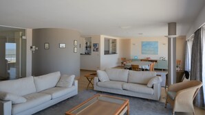 En moderne stue med to sofaer, et sofabord og et spiseområde med bord og stole.