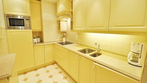 A kitchen with yellow cabinets, a microwave, a sink, and a coffee maker.