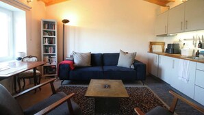 Un salon chaleureux avec un canapé bleu foncé, une table basse en bois et une bibliothèque.