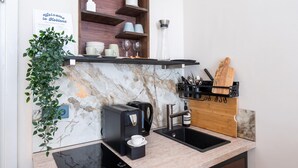 Een moderne keuken met een marmeren spatwand, een koffieapparaat, een spoelbak en een houten snijplank.