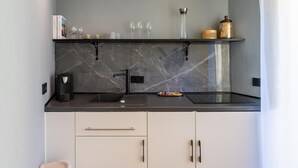 A modern kitchen with a marble backsplash, black countertop, and white cabinets.