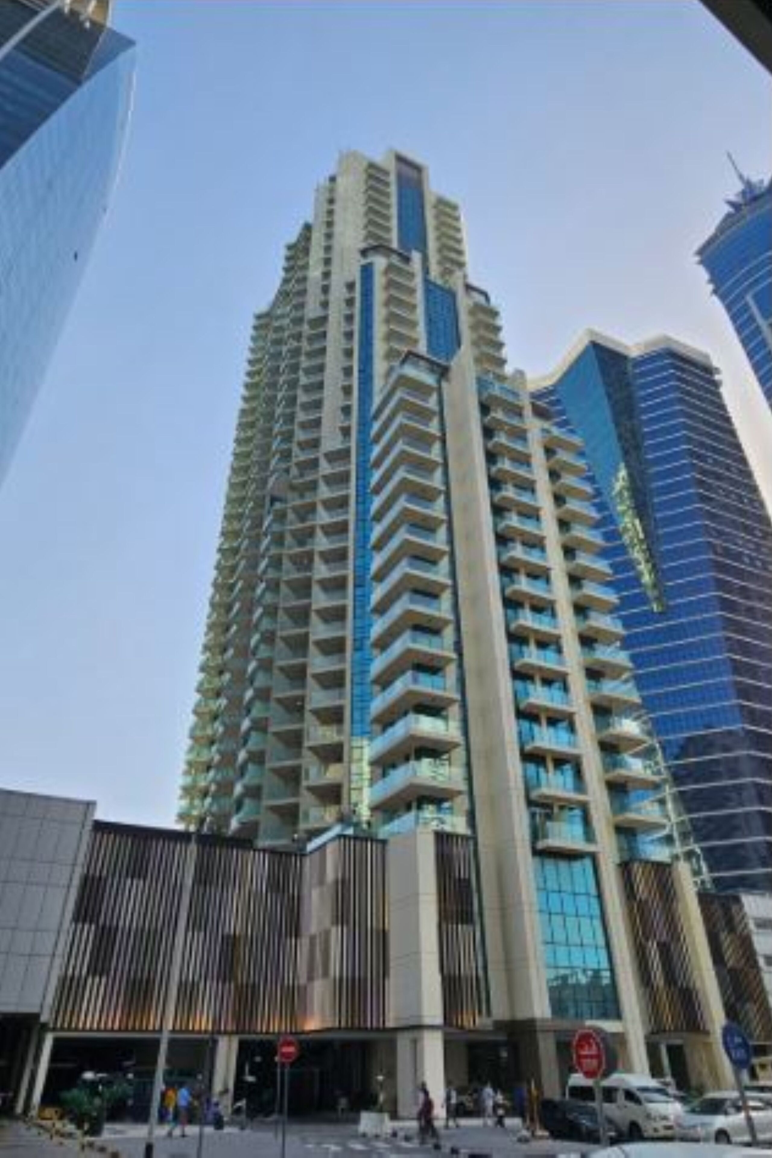 A high-rise building with a modern architectural design, featuring multiple balconies and a glass facade.