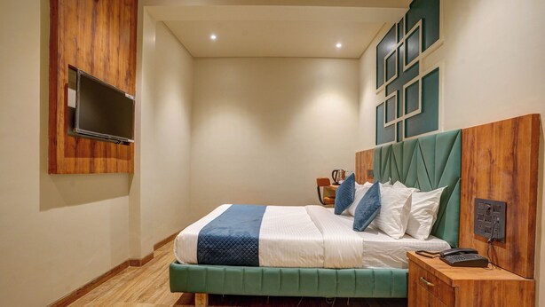Een slaapkamer met een bed, nachtkastje en een wandgemonteerde televisie.