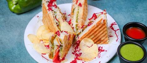 A plate of sandwiches with chips and two dipping sauces.