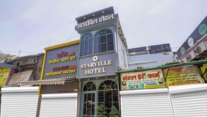 Een hotel met een bord waarop 'Starville Hotel' staat, en een bord voor een restaurant en bar eronder.
