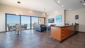 A modern interior with a kitchen, dining area, and a balcony with a view of the sea.