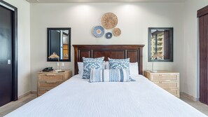 Un dormitorio con una cama grande, dos mesitas de noche, un cabecero de madera y tres placas decorativas colgadas en la pared.