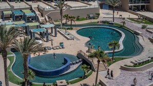 Un complexe hôtelier doté d’une grande piscine, d’espaces de détente en plein air et de palmiers.