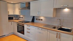 A modern kitchen with white cabinets, a stainless steel sink, and a microwave.