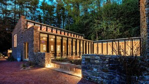 A modern house with a stone exterior, large glass windows, and a gravel driveway. - Historic Retreat in Peak District by River Dane (Wildboarclough)