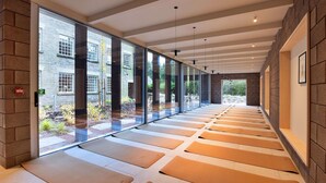 A corridor with large windows, a brick wall, and yoga mats on the floor. - Historic Retreat in Peak District by River Dane (Wildboarclough)