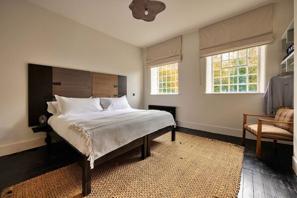 A bedroom with a bed, a chair, a window, and a radiator.