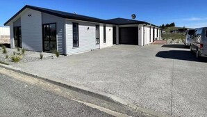 A two-story building with a garage, a driveway, and a parked car. - April Three Bedroom Apartment (Lake Tekapo)