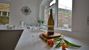A kitchen counter with a wine bottle, glasses, and tulips.