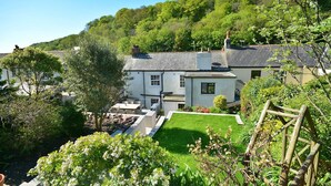 A residential property with a well-maintained lawn, a patio area, and a view of a hill with dense greenery.