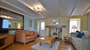 A living room with a wooden coffee table, two sofas, a television, and a fireplace. - Cottage in Cawsand near Sandy Beach (Cawsand)