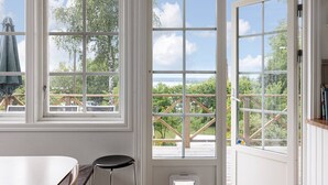 A room with large windows, a wooden deck, and a view of greenery and water. - Ref. 534251 (Saltsjö-Boo)