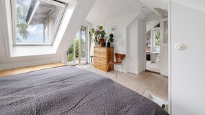 A bedroom with a sloped ceiling, a bed, a dresser, a chair, and a large window. - Ref. 534251 (Saltsjö-Boo)