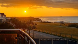 A coastal sunset view with a beach, a pier, and a gazebo.
