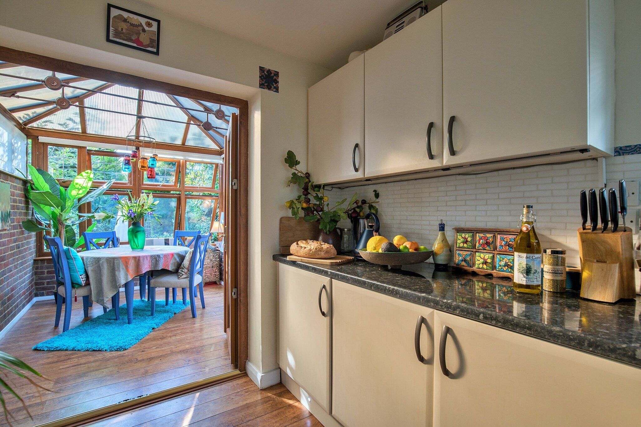 A kitchen with white cabinets, a granite countertop, and a dining area with a table and chairs.