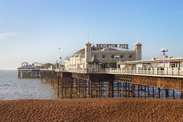Une jetée sur laquelle se trouve un bâtiment portant l’inscription « Brighton Pier », avec un grand dôme et deux tours.