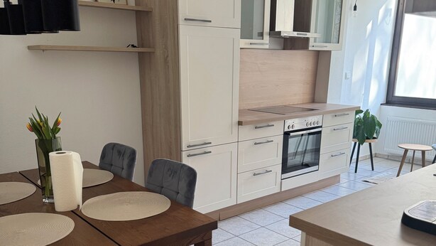 Eine moderne Küche mit weißen Schränken, einem eingebauten Backofen und einem Fenster für natürliches Licht.