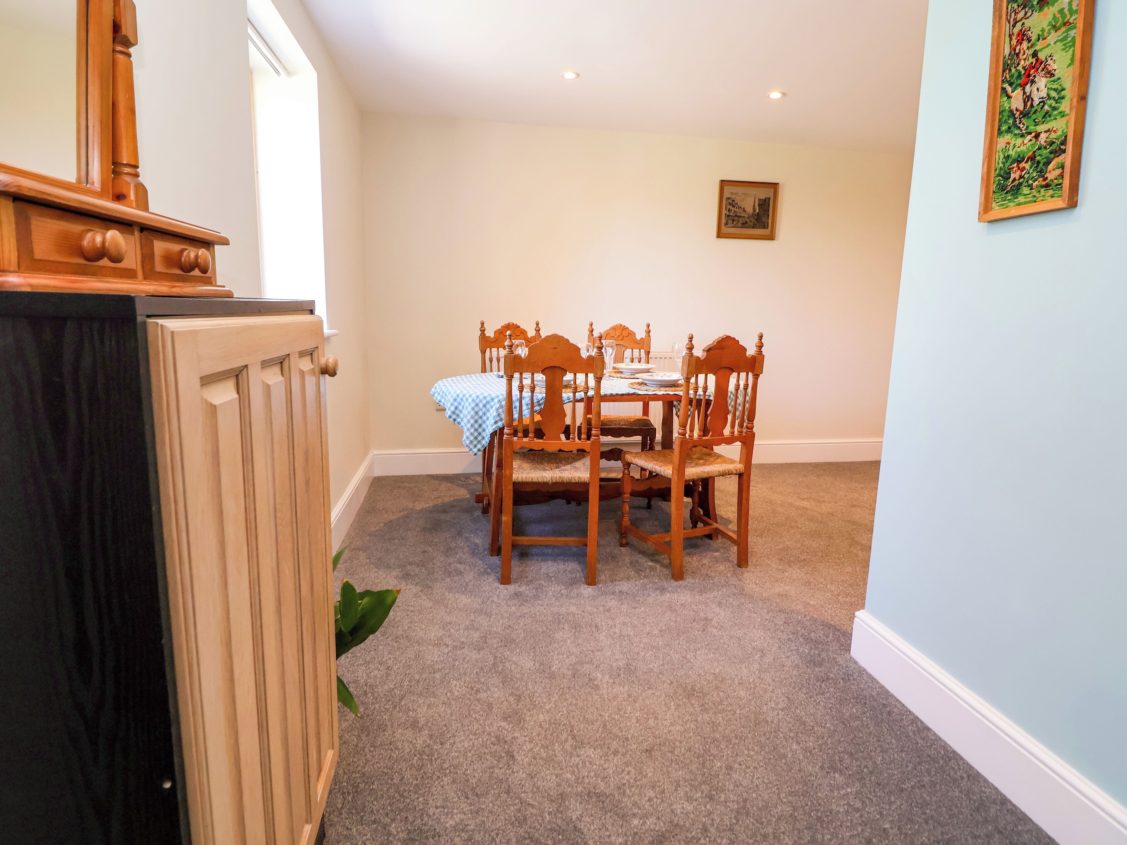 A dining area with a table set for four, surrounded by wooden chairs.
