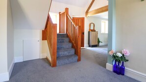 Una escalera con barandillas de madera y peldaños alfombrados que conduce a una plataforma.