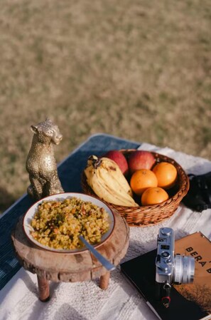 Ein Tisch mit einer Schüssel Essen, einem Obstkorb, einer Kamera und einem Buch.