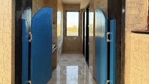A corridor with blue doors leading to a room with a view of a tree. - Jawai Retreat - Jawai (Bali)