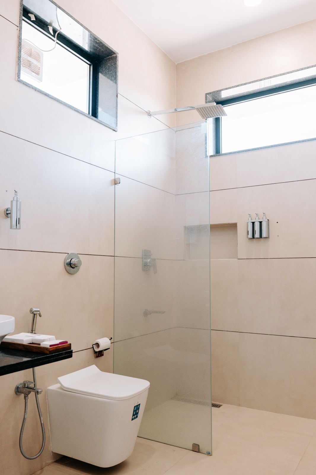 A modern bathroom with a glass-enclosed shower, a toilet, and a sink.