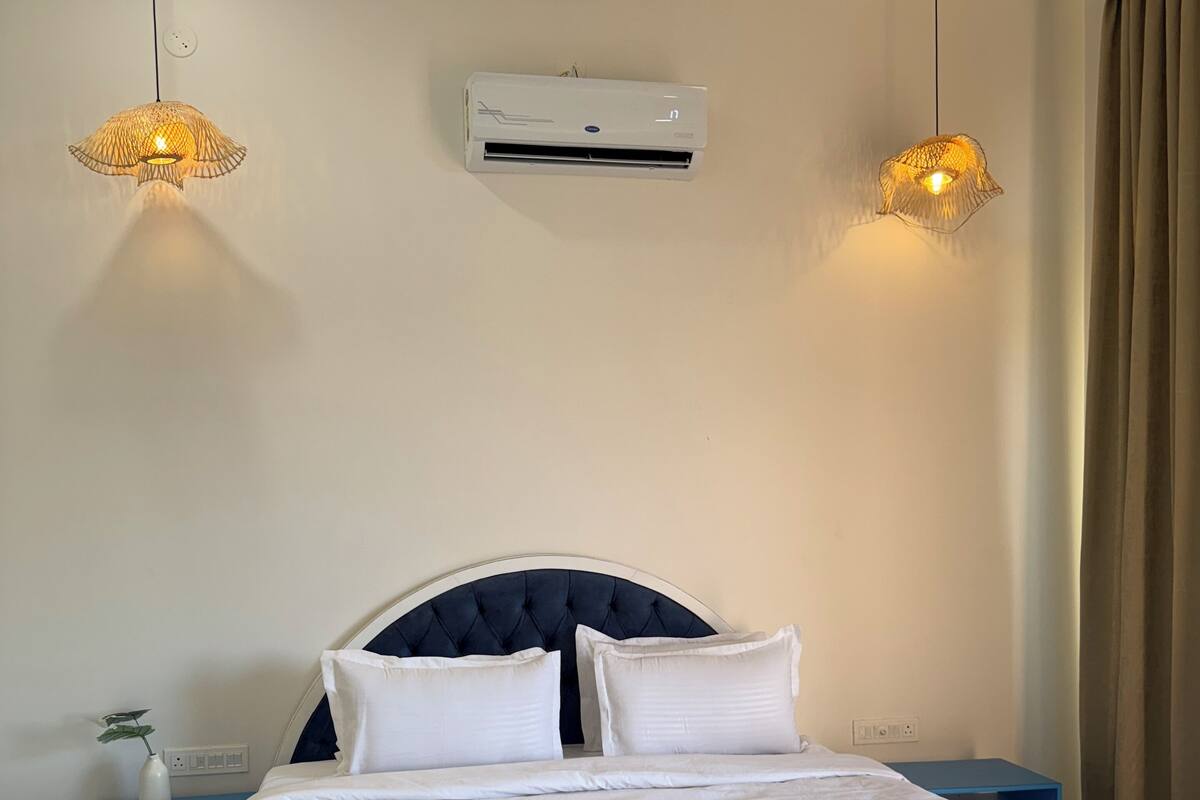 Een netjes ingerichte slaapkamer met een bed, nachtkastjes en een wandairconditioner.