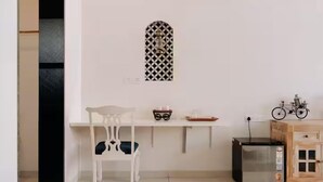 A small kitchenette with a white chair, a shelf with a decorative item, a bicycle, and a refrigerator. -  Jaadooghar Aravalli Hideaway Jawai (Bali)