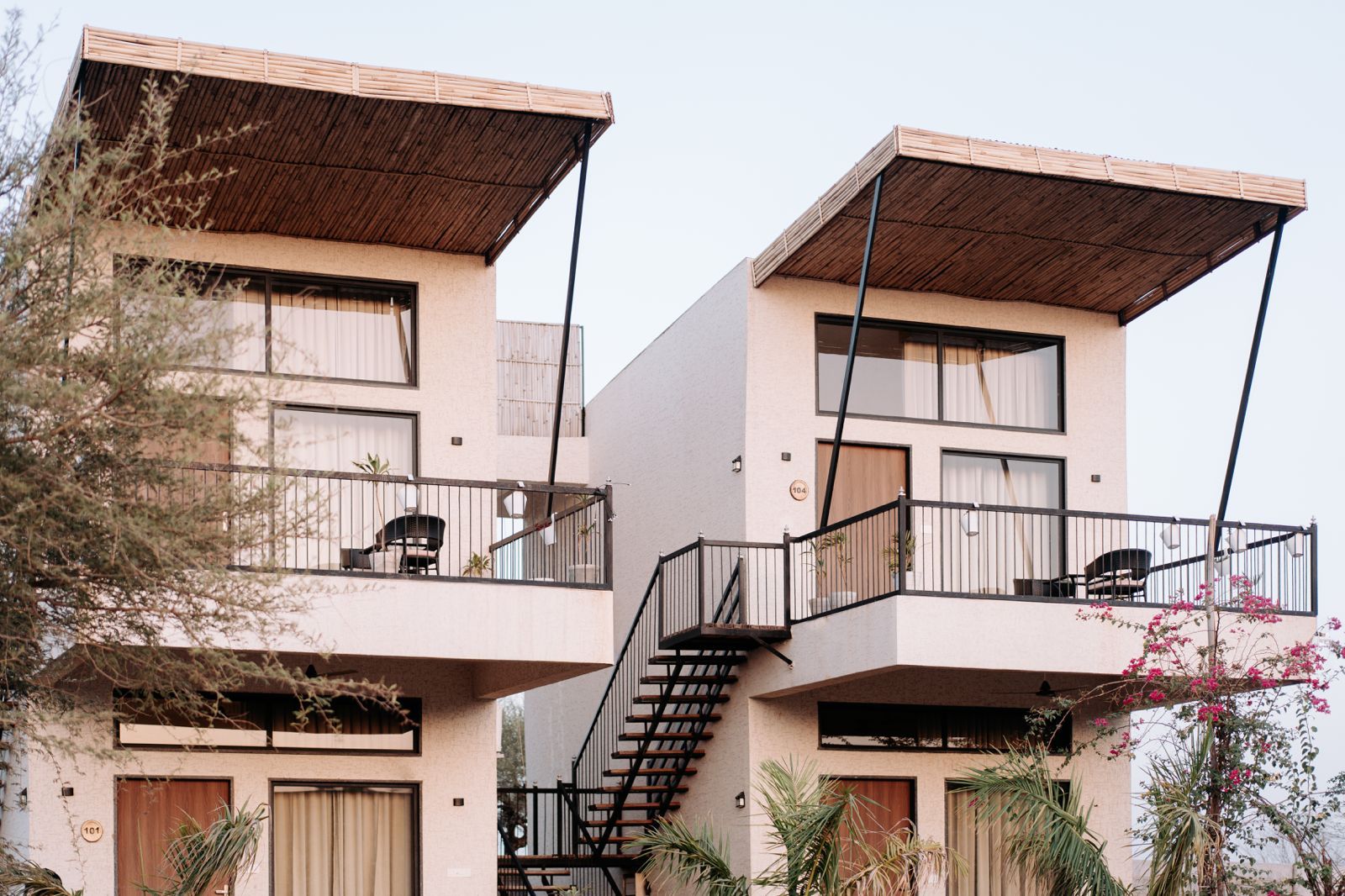 Un edificio moderno con balcones de dos pisos, una escalera y un techo plano.