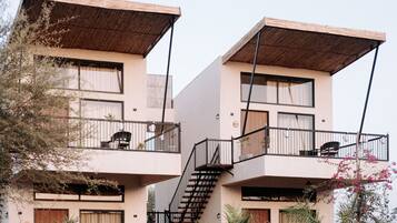 Un edificio moderno con balcones de dos pisos, una escalera y un techo plano.
