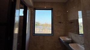 A modern bathroom with a large window, two sinks, and a mirror. -  Jaadooghar Aravalli Hideaway Jawai (Bali)