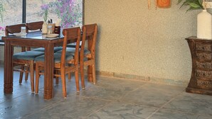 A dining area with a table and chairs, an air conditioning unit, and a wall-mounted utensil rack. -  Jaadooghar Aravalli Hideaway Jawai (Bali)
