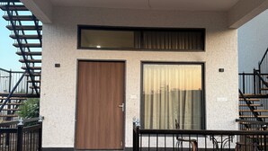 A modern building with a wooden door, large windows, and a balcony with outdoor furniture. - Jawai Retreat - Jawai (Bali)