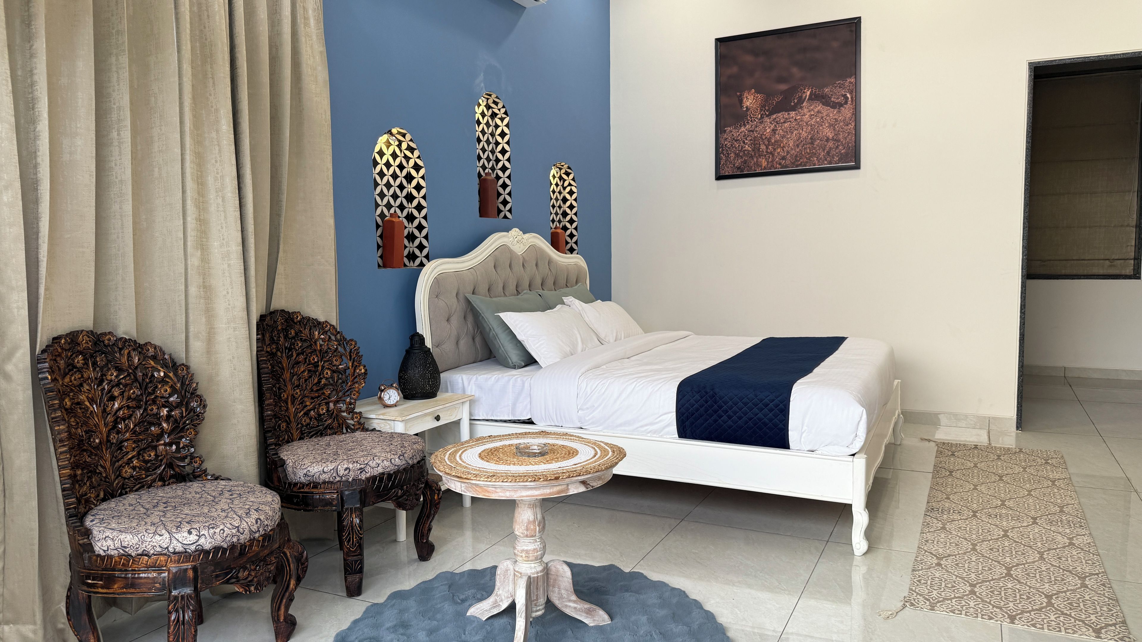 Ein Schlafzimmer mit einem Bett, zwei Stühlen, einem kleinen Tisch und Wanddekoration.